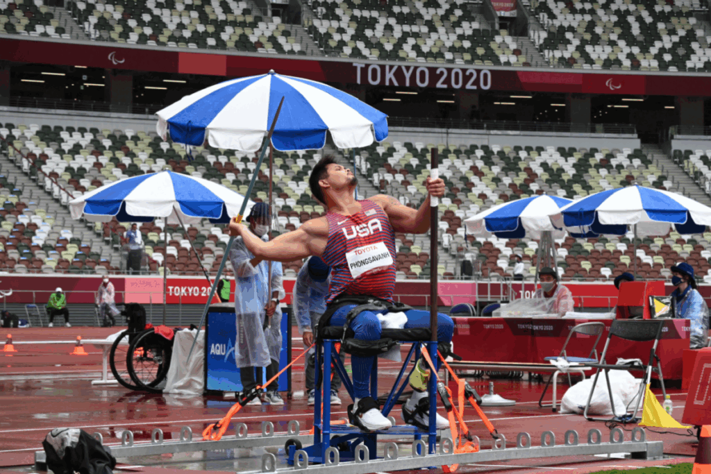 Paralympic javelin thrower in a USA uniform prepares to throw from a seated throwing frame during competition at Tokyo 2020.