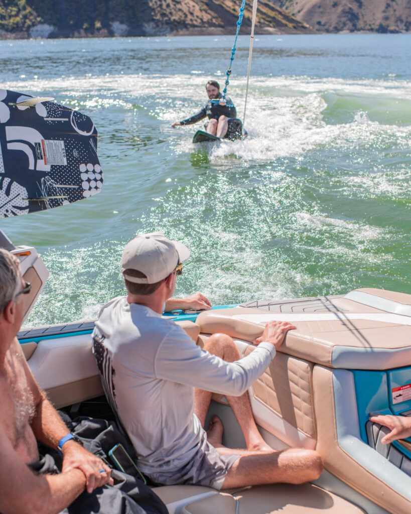 A man wakeboarding on a lake with spectators watching from a boat.