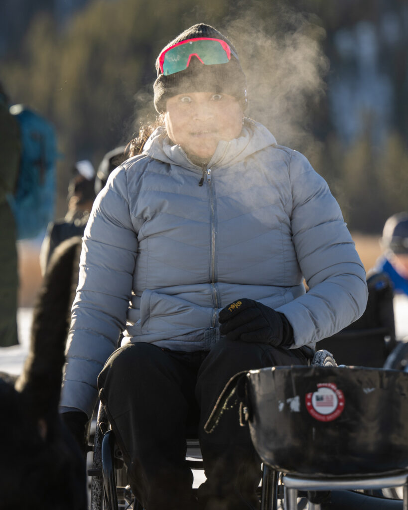 A person in a wheelchair, with visible breath in cold air.