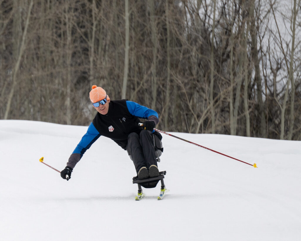 A skier using a mono-ski to navigate a snowy slope.