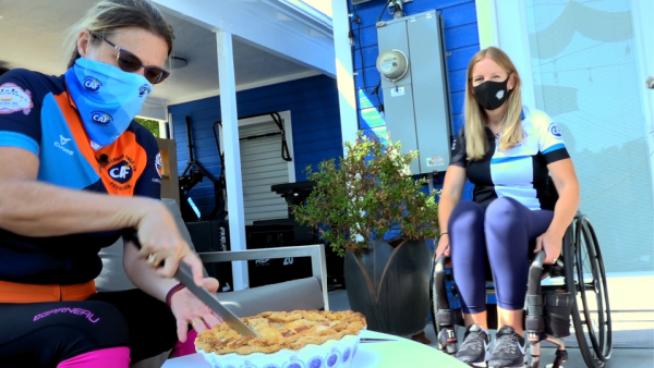 Amy cuts a homemade pie while friends chat nearby, continuing the Ride for Pie Day tradition.