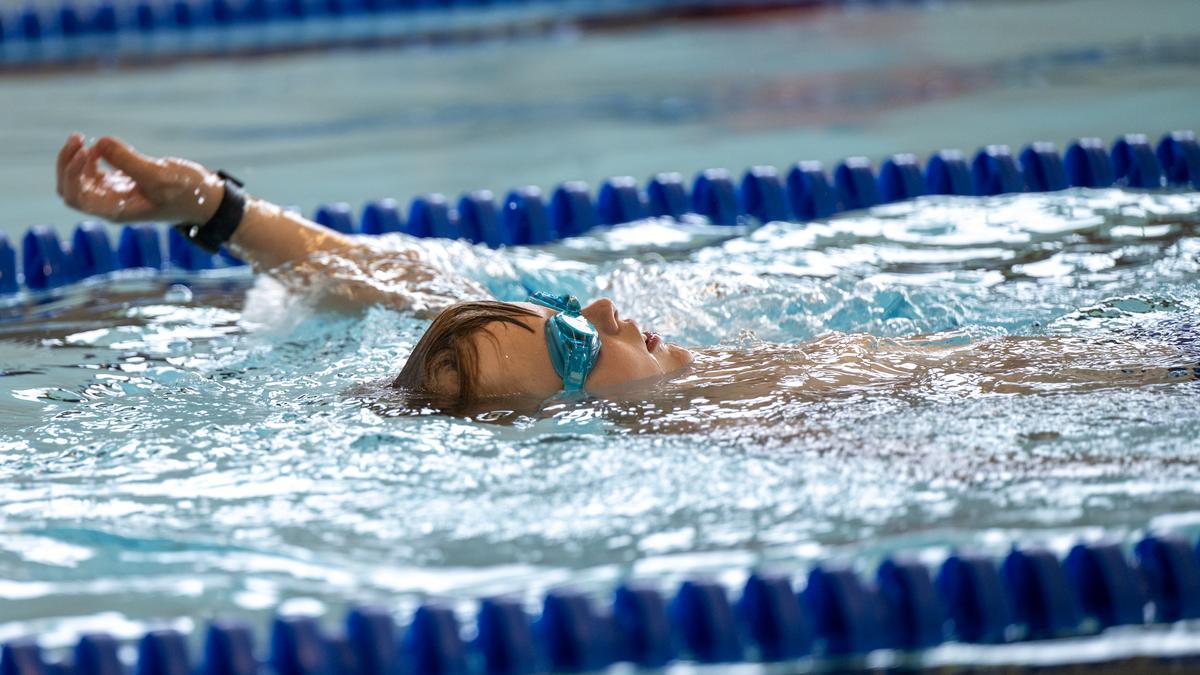 A young athlete wearing goggles floats on their back in a pool during the swim portion of the Idaho Kids Paratriathlon Camp.