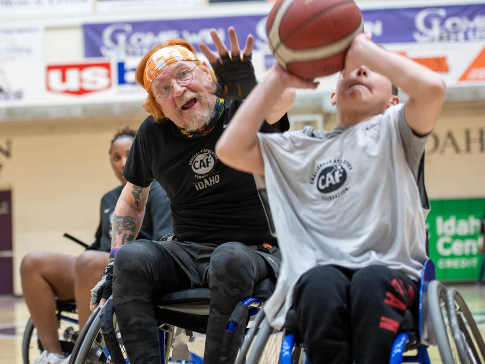 Two people playing wheelchair basketball in a gym.