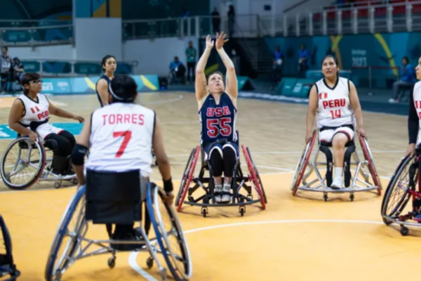 USA wheelchair basketball athlete takes a shot while surrounded by Peru wheelchair basketball players during an international tournament game.