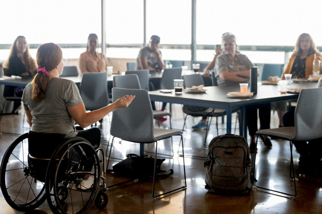 A speaker using a wheelchair addresses a group during an inclusive community session.