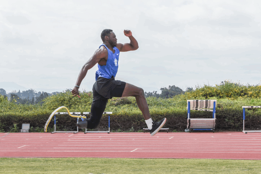 Track and field athlete with a running blade leaps midair during a training session on a track.