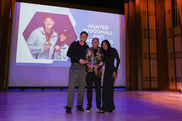 CAF award presenters and honorees Hunter Woodhall and Tara Davis-Woodhall pose on stage with CAF’s Bob Babbitt during the Celebration of Abilities Awards Ceremony at The Conrad Prebys Performing Arts Center.