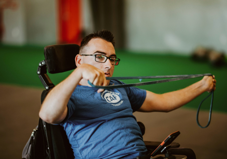 Athlete using a resistance band from a power chair during an indoor workout.