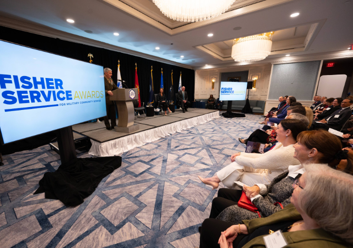 Attendees seated in a ballroom watch the Fisher Service Awards presentation from the audience.