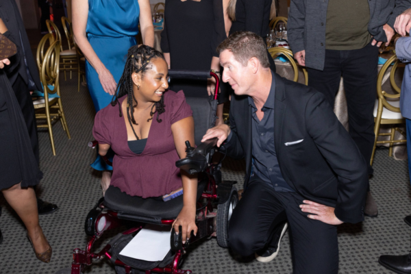 Guests pose on the red carpet at the Challenged Athletes Foundation Defying Limits Gala, including an athlete with a physical disability in a wheelchair, in front of a step-and-repeat featuring CAF and Defying Limits branding.