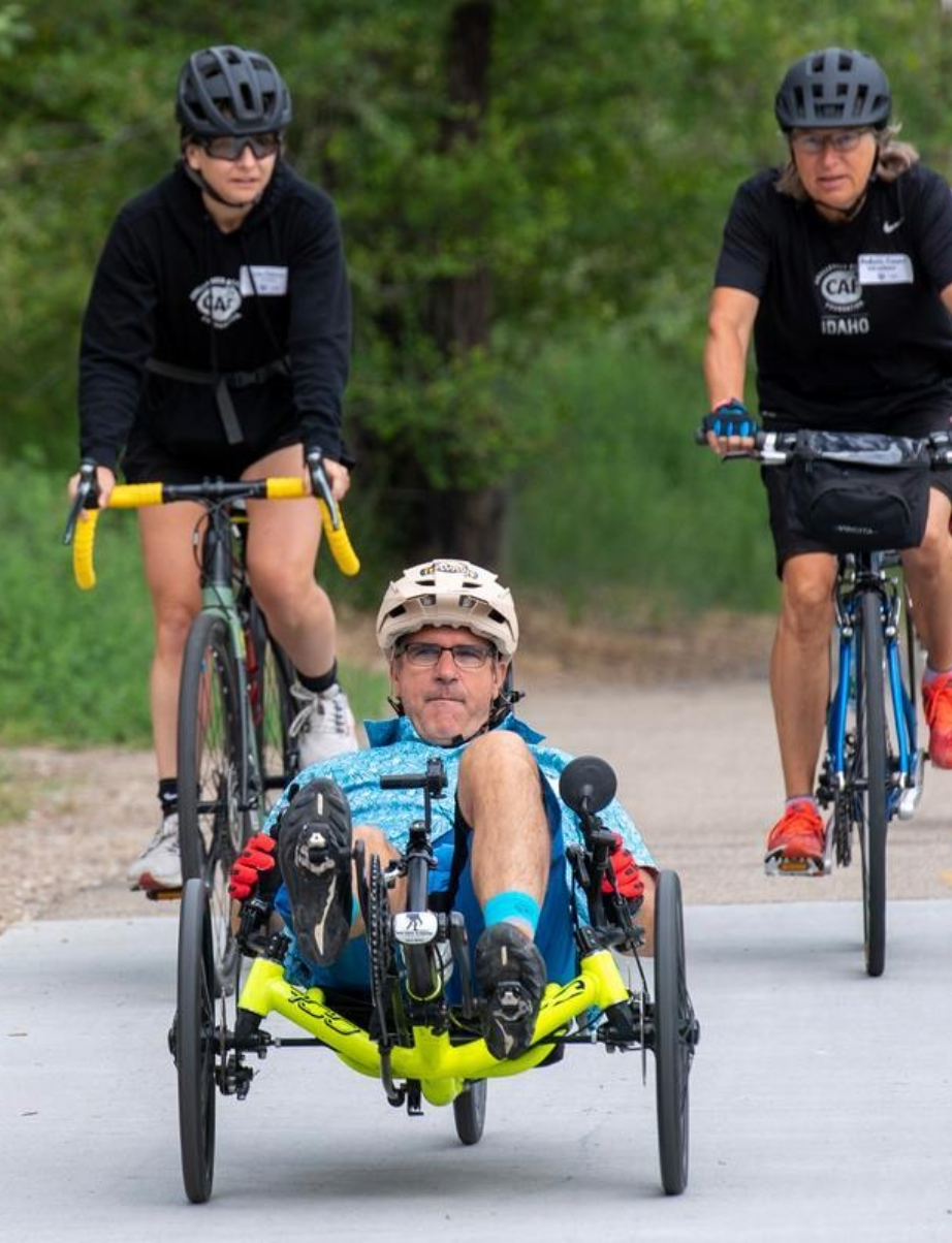 Inclusive cycling group trains together on a scenic path, with a handcycle rider at the front and cyclists following.