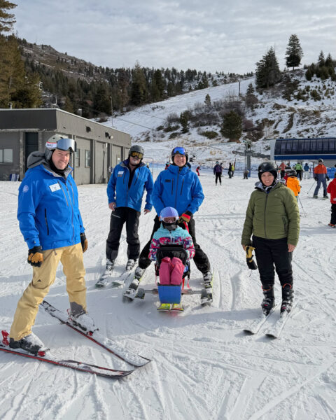 Group of skiers with a ski sled at a snowy slope.
