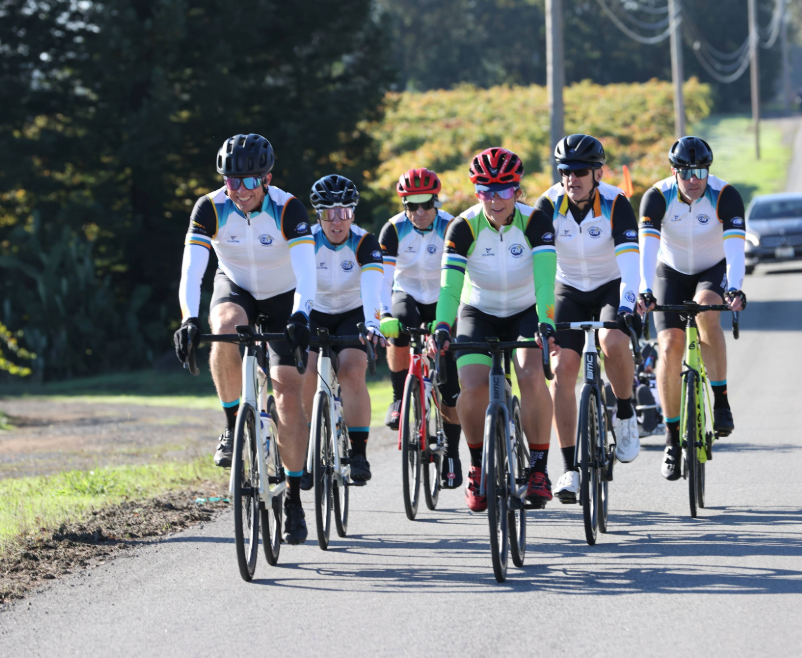 Group of cyclists riding together on a road in a tight formation.