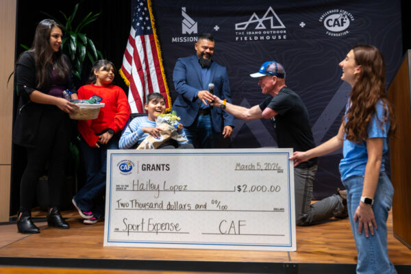 People presenting a large check to a child in a wheelchair on stage.