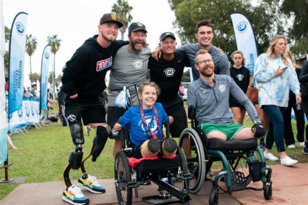 Group of CAF athletes with physical disabilities and supporters pose together outdoors, celebrating community and connection.