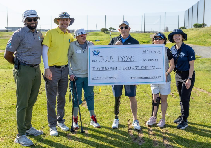Group holding a large grant check for $2,000 on a golf course.