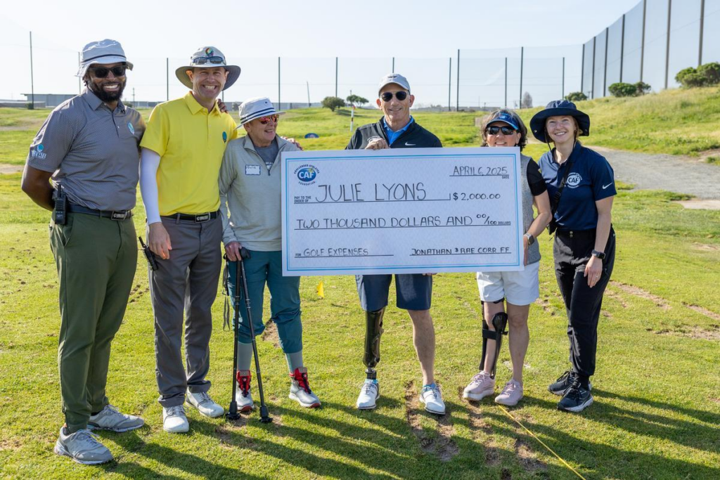 Group holding a large grant check for $2,000 on a golf course.