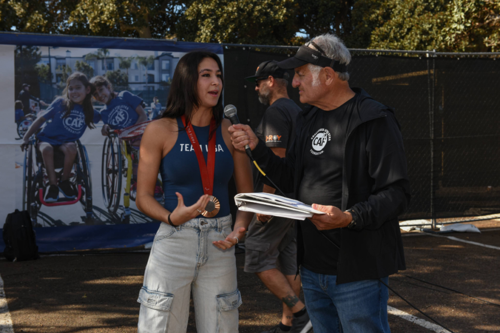 Beatriz Hatz speaks during an interview at a CAF event while wearing a competition medal.