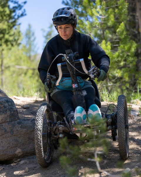 Person in an adaptive off-road cycle on a forest trail.