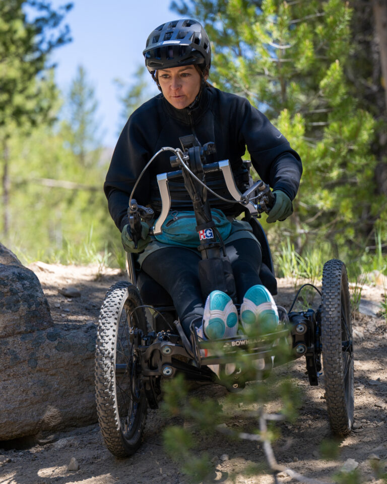 Person in an adaptive off-road cycle on a forest trail.