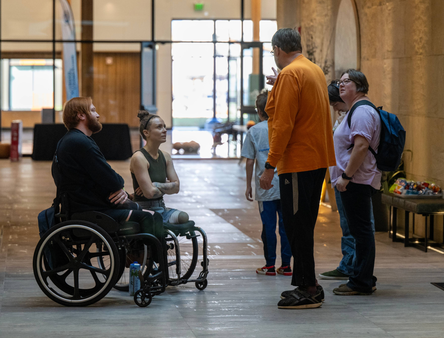 Symposium attendees, including participants with limb differences and wheelchair users, connect and chat in a lobby during a CAF Idaho Symposium gathering.