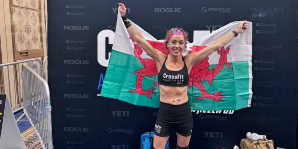 Hannah Webster holds a Welsh flag while posing at the CrossFit Adaptive Games competition venue.