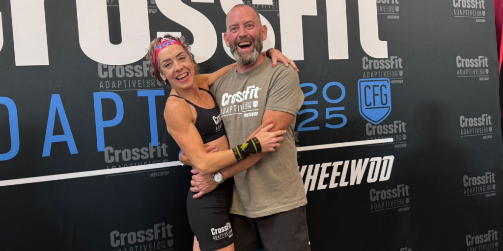 Hannah Webster and a fellow CrossFit Adaptive Games participant pose together in front of event signage.