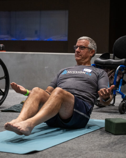 A man doing yoga in an indoor setting, on his back with knees up.