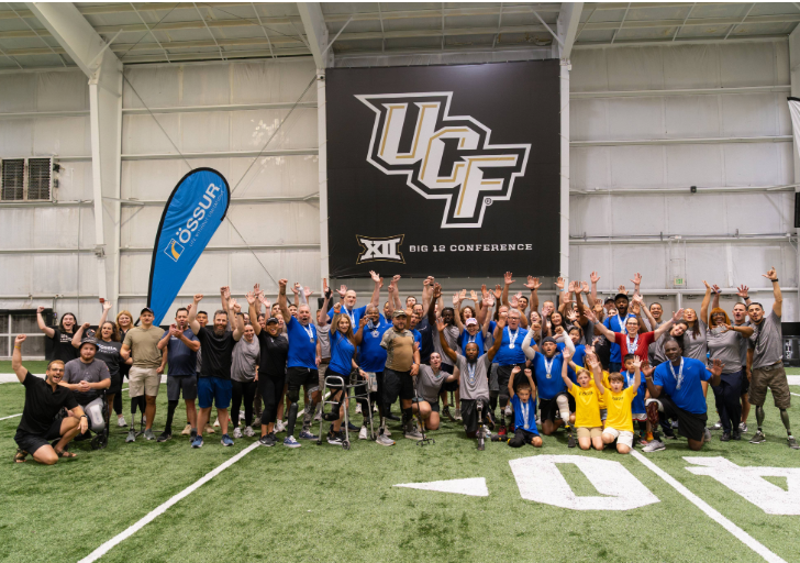 Participants and supporters pose together during the CAF and Össur Running and Mobility Clinic at the University of Central Florida indoor athletic facility.