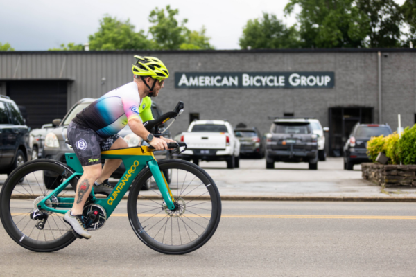 Cyclist riding a Quintana Roo bicycle on a roadway outside the American Bicycle Group facility.