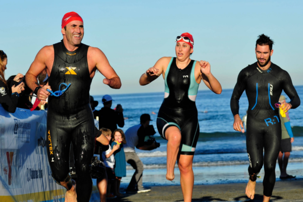 Athletes exit the ocean during a triathlon swim segment at a Challenged Athletes Foundation endurance sports event.