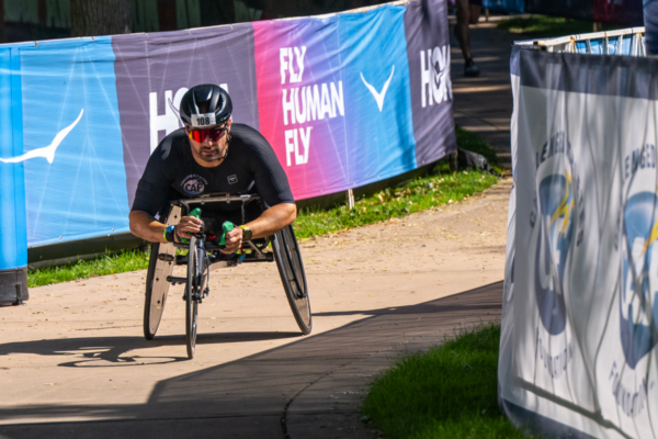 CAF athlete rides a racing handcycle along the IRONMAN 70.3 Boise course during an adaptive sports event.