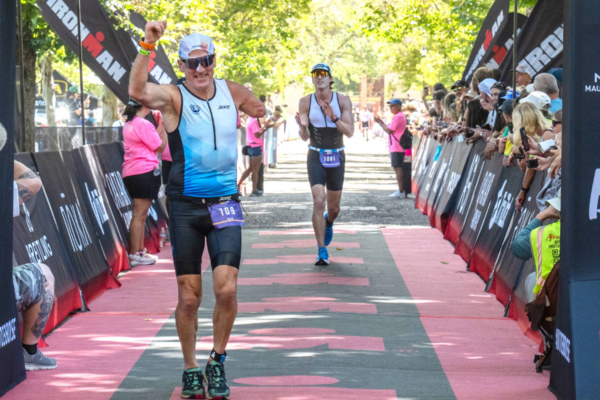 CAF athlete crosses the finish line at IRONMAN 70.3 Boise as spectators line the adaptive triathlon course.