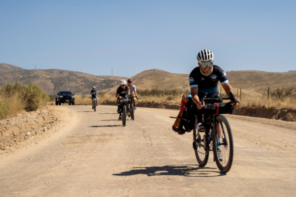 Cyclists participating in the Challenged Athletes Foundation and Triathlon Across America ride along a rural road during a multi-day endurance journey. Provide your feedback on BizChat