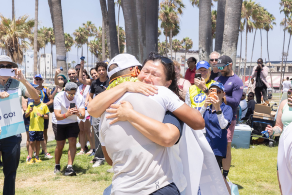 Mohamed Lahna embraces a supporter after finishing Triathlon Across America as members of the adaptive sports community and spectators look on.