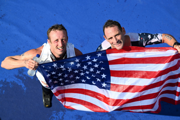 Two Paralympic athletes holding a United States flag after completing a Para triathlon event.