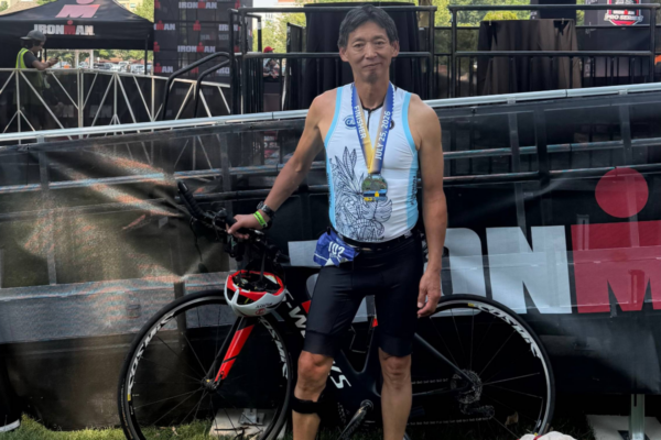 Challenged Athletes Foundation athlete standing beside a road bike while wearing a finisher medal after completing IRONMAN 70.3 Boise.