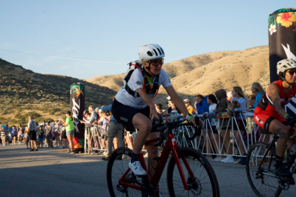 Challenged Athletes Foundation cyclist competing during the bike segment of IRONMAN 70.3 Boise with spectators lining the course.