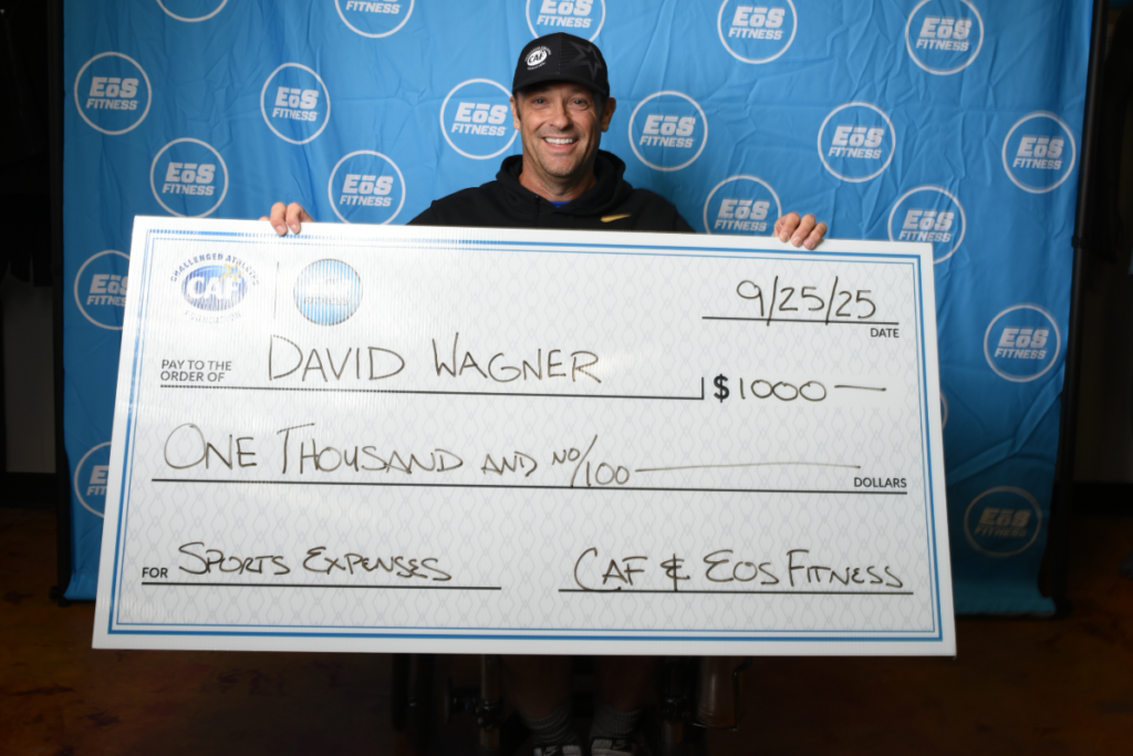 David Wagner holding a $1,000 CAF Sport Expense Grant check presented with EōS Fitness.