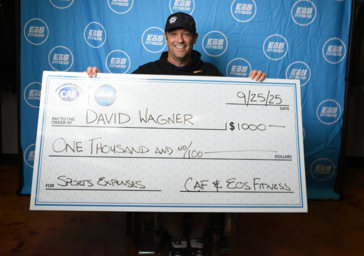 David Wagner holding a $1,000 CAF Sport Expense Grant check presented with EōS Fitness.