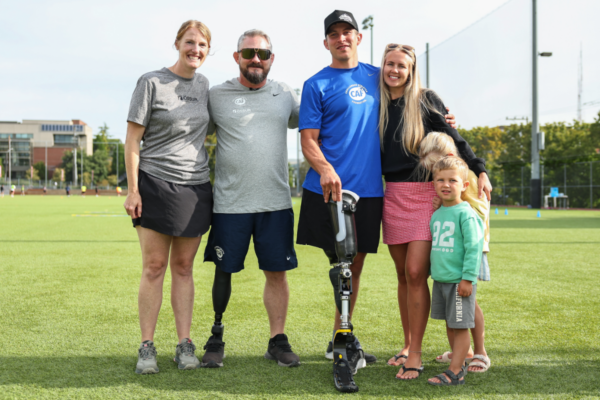 Adaptive athlete using a lower limb prosthesis stands with family members and clinic participants during a Challenged Athletes Foundation and Össur adaptive running clinic in Seattle.