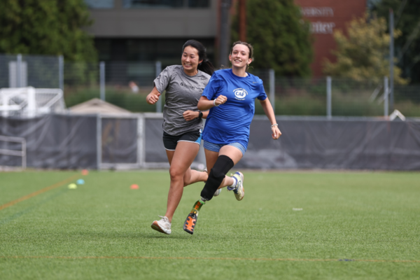 Adaptive athlete with a running blade prosthesis runs alongside a coach during an adaptive running clinic hosted by Challenged Athletes Foundation and Össur.