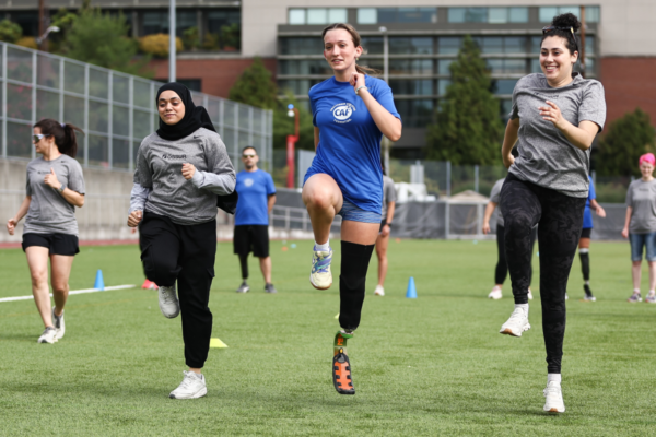 Participants perform high-knee running exercises on a sports field during a Challenged Athletes Foundation and Össur adaptive running clinic.