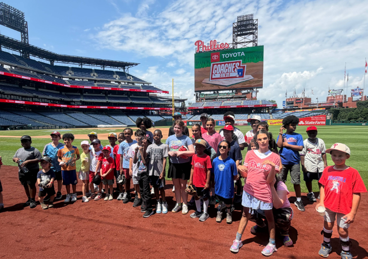 Participants gather on the field at Citizens Bank Park during the Toyota Phillies Coaches Clinic, standing together for a group photo near the infield.