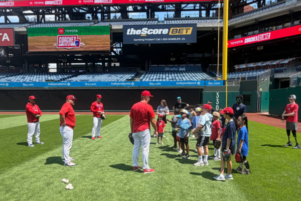Philadelphia Phillies coaches provide on-field instruction to youth participants gathered on the grass during the Toyota Phillies Coaches Clinic at Citizens Bank Park.