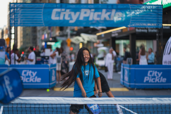 Youth participant stands on a CityPickle court during a Challenged Athletes Foundation adaptive pickleball clinic in New York City.