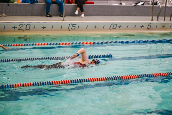 An adaptive athlete swims freestyle in a pool during a swim session at the CAF Northeast Paratriathlon Clinic.