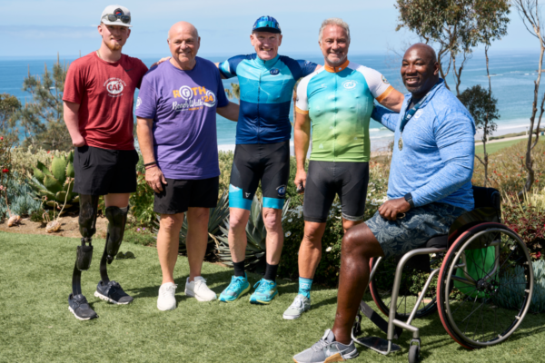 Challenged Athletes Foundation athletes, supporters, and cyclists gather overlooking the Pacific Ocean during a CAF community event celebrating adaptive sports and inclusion.
