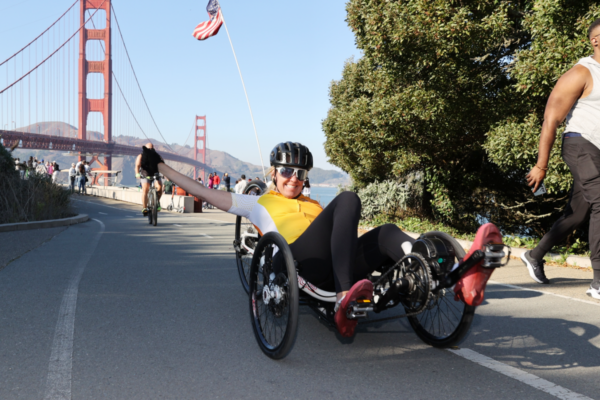 Adaptive athlete rides a handcycle along the San Francisco waterfront near the Golden Gate Bridge during a CAF endurance event.