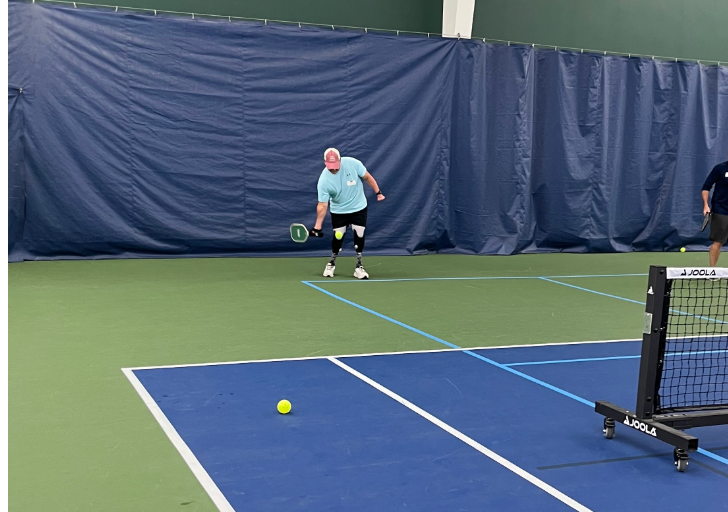 Jeff Belcher plays tennis on an indoor court using lower-limb prostheses.
